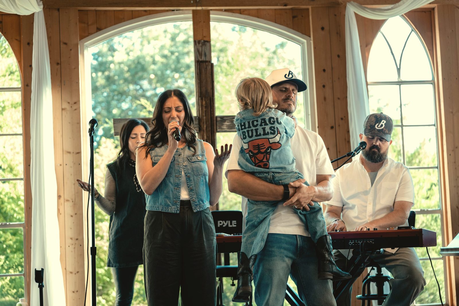 The worship team leading a Tend Gathering in front of tall arched windows