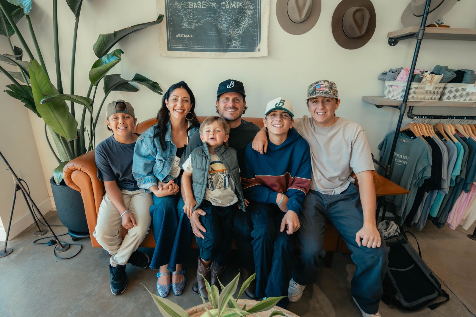 Theo and Rachel Koulianos smiling on a leather couch with their four sons