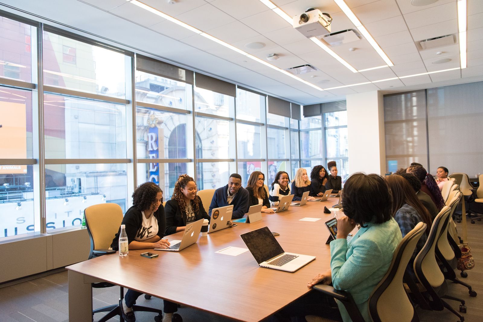 A full company team smiling and talking together around a long boardroom table